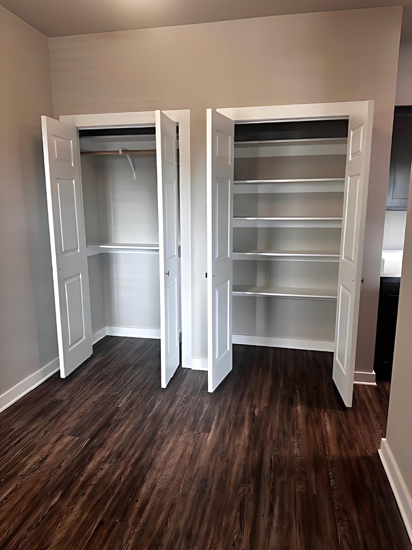 A room with two open closets and wood flooring.